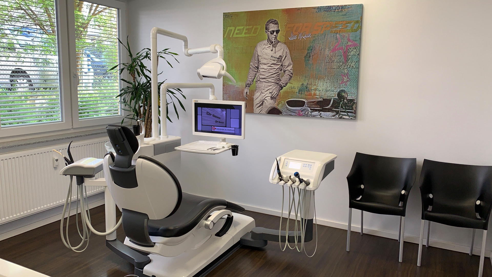 Behandlungszimmer mit modernem Behandlungsstuhl, Monitor und Steve-McQueen-Kunstdruck